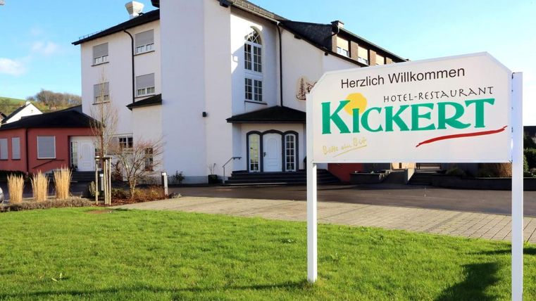 Ein einladendes Hotel-Restaurant mit dem Namen "Kickert". Die Fassade ist modern und umgeben von grünem Rasen.