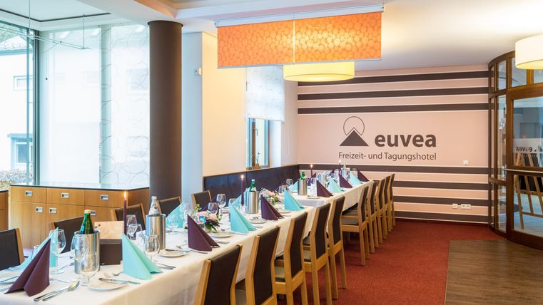 Ein eleganter Speisesaal mit gedeckten Tischen, dekoriert mit bunten Servietten. Der Raum ist hell und modern, ideal für Veranstaltungen.