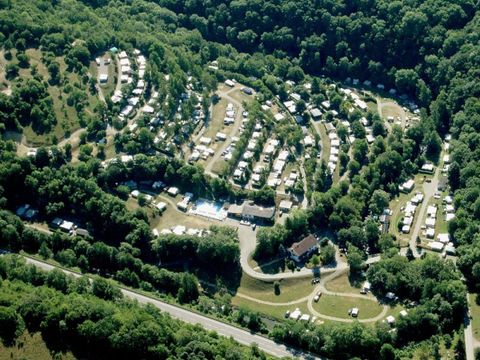 Eine Luftaufnahme eines Campingplatzes mit vielen Stellplätzen, umgeben von einem Wald. Die Wege zwischen den Stellplätzen sind gut erkennbar.