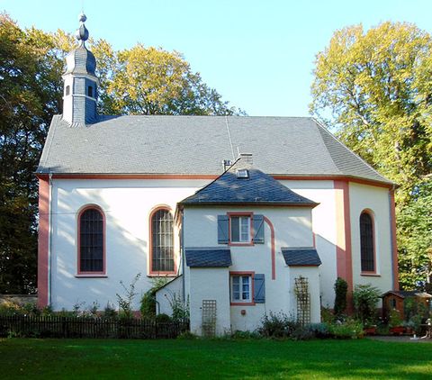 Schankweiler Klause, eine kleine Kapelle mit angrenzendem Gebäude, umgeben von Bäumen und einem Garten.