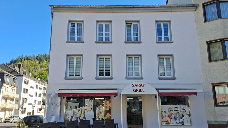 Een restaurant genaamd "Saray Grill" met een uitnodigende buitengevel. Voor het gebouw staan tafels en stoelen voor gasten buiten.