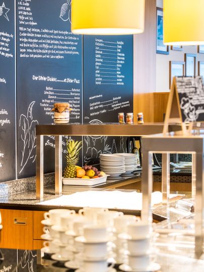 Eine moderne Café-Lounge mit einem stilvollen Tresen. Auf dem Tisch stehen Stapel von Tassen und frisches Obst.