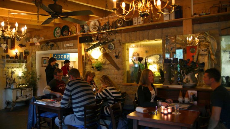 Ein gemütliches Restaurant mit Holzdekor und warmem Licht. Gäste sitzen an Tischen und genießen ihre Zeit in einer einladenden Atmosphäre.