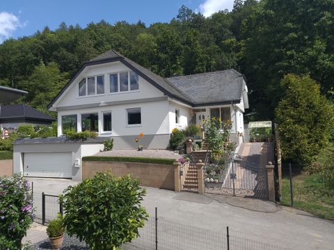 Een modern huis met een mooie tuin en een oprit. Achter het huis staan bomen die de omgeving een groene tint geven.