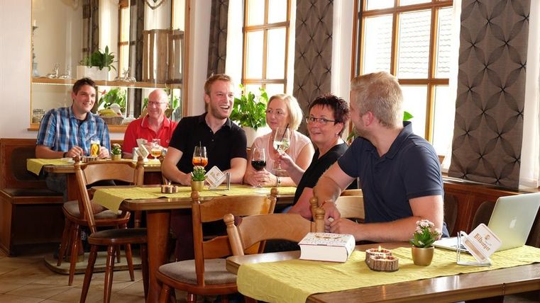 Eine Gruppe von Menschen sitzt in einem gemütlichen Restaurant. Sie lächeln und stoßen mit Getränken an.