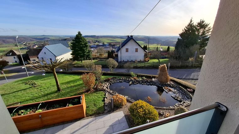 Eine schöne Aussicht auf eine ländliche Umgebung mit einem Teich und mehreren Häusern. Die Landschaft ist grün und von Bäumen umgeben.