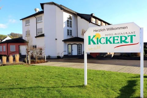 Ein einladendes Hotel-Restaurant mit einem gepflegten Rasen. Der Schild begrüßt die Gäste und zeigt den Namen "Kickert".