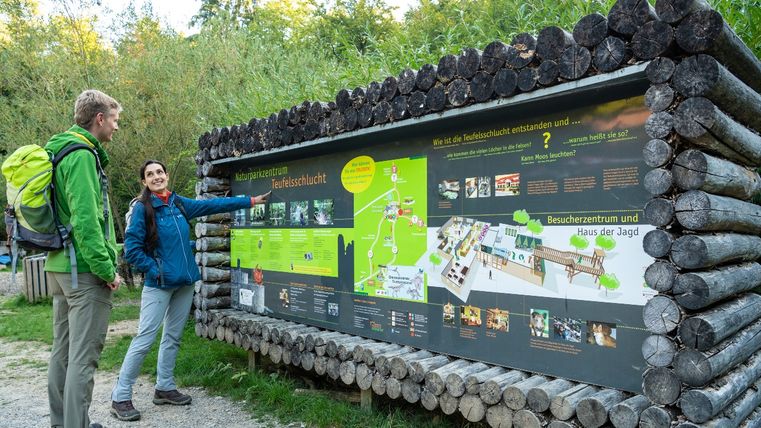 Zwei Personen betrachten eine Informationstafel im Naturparkzentrum Teufelsschlucht.