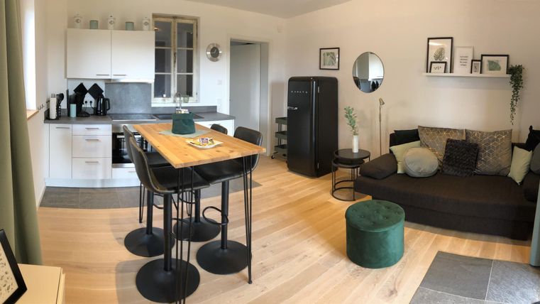 Een lichte en moderne woning met een open keuken en een gezellige woonkamer. De inrichting is stijlvol en uitnodigend, met een eettafel en een hoekbank.