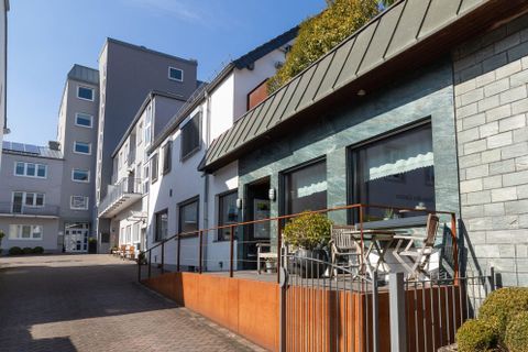 Ein modernes Gebäude mit einer Glasfassade und einem begrünten Außenbereich. Die Architektur ist zeitgemäß und lädt zum Verweilen ein.