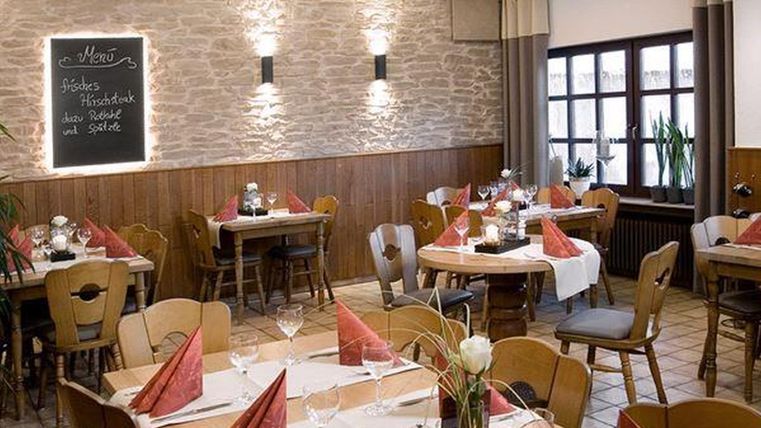 Ein einladendes Restaurant mit rustikalem Ambiente. Tische sind liebevoll gedeckt, und es gibt eine Tafel mit dem Menü.