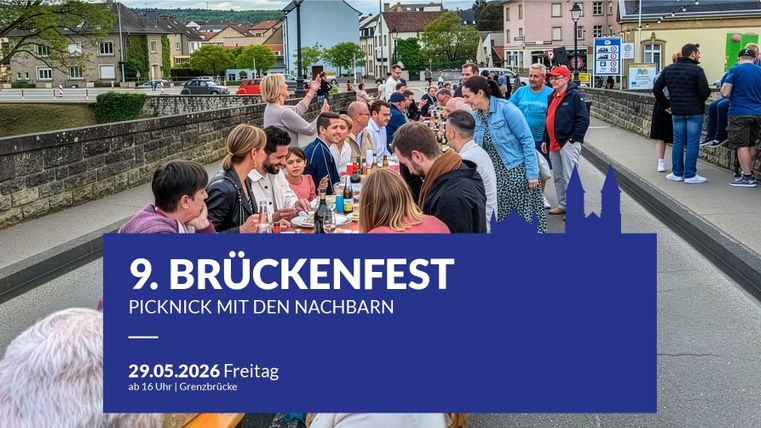 Eine belebte Brücke mit vielen Menschen, die über einen Fluss führt. Im Hintergrund sind malerische Häuser und etwas Grün sichtbar.