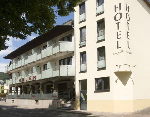 Ein modernes Hotel mit dem Namen "Hauer" und großen Fenstern. Die Fassade ist hell und hat einen einladenden Außenbereich.