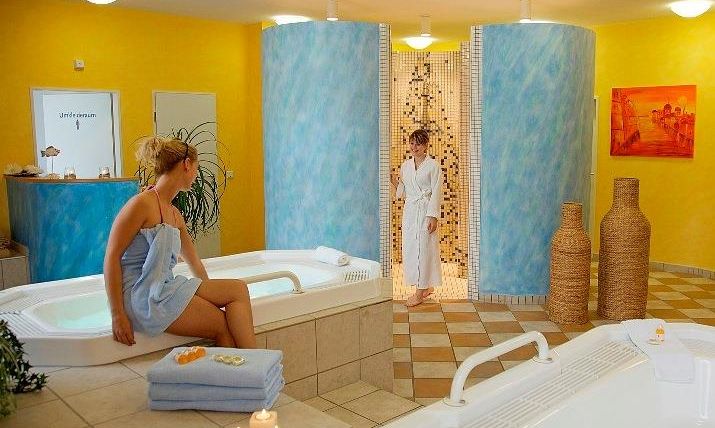 Ein entspannendes Spa mit Whirlpools und sanfter Beleuchtung. Eine Frau sitzt in einem Bademantel und genießt die ruhige Atmosphäre.