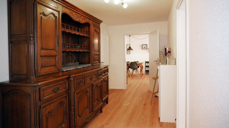 Ein gemütlicher Flur mit einem klassisch gestalteten Holzschrank. Der lange Flur verbindet die Zimmer.