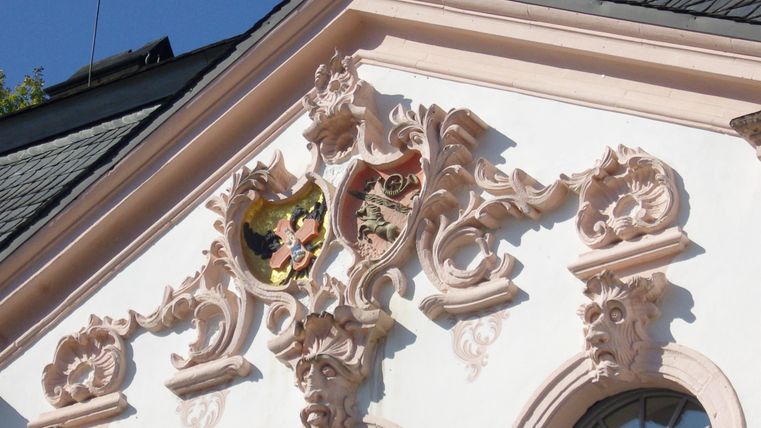 Ein schöner Gebäudeverzier mit filigranen Details und einem Wappen. Der Himmel ist klar und die Architektur ist beeindruckend.