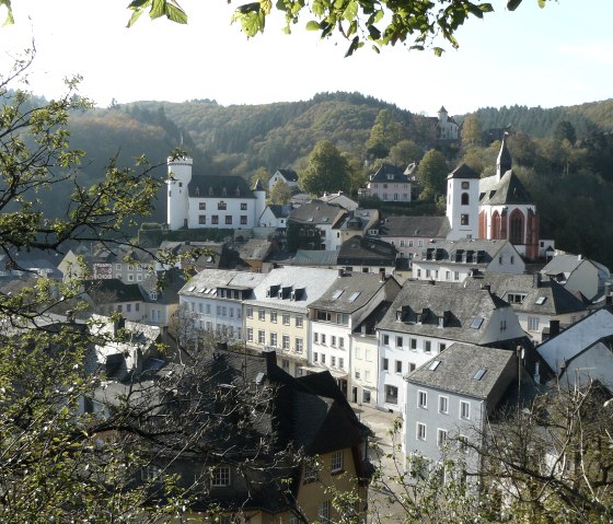 Vue panoramique de Neuerburg avec des bâtiments historiques, une église et des collines boisées en arrière-plan., © Christian Calonec-Rauchfuss, Felsenland Südeifel Tourismus GmbH