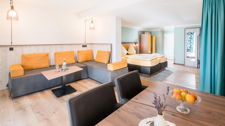 Eine moderne Wohnung mit einem gemütlichen Wohnbereich und einer Esszeile. Der Raum ist hell und freundlich gestaltet, mit einer Kombination aus neutralen und bunten Möbeln.