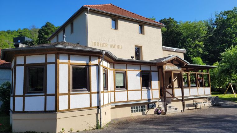 Ein charmantes Gebäude mit holzverkleidetem Erdgeschoss und einem hellen Obergeschoss. Umgeben von Grünflächen, strahlt es eine einladende Atmosphäre aus.