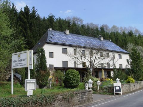 Ein modernes Haus mit Solarpanelen auf dem Dach. Umgeben von Bäumen und einem gepflegten Garten.