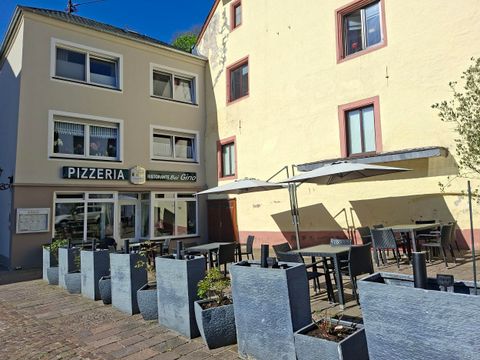 Une pizzeria avec une terrasse dans une rue charmante. Des tables et des chaises sont disposées sous des parasols.