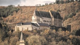 Das Schloss Vianden thront majest&auml;tisch auf einem H&uuml;gel, umgeben von herbstlich gef&auml;rbten B&auml;umen und einem bew&ouml;lkten Himmel., &copy; Jengel