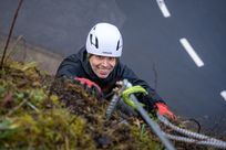 Kletterer an Felswand schaut nach oben in Kamera