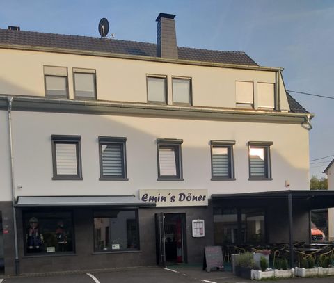 Ein Restaurant namens "Emin's Döner" in einem modernen Gebäude. Die Fassade ist hell, mit Fenstern und einem überdachten Außenbereich.