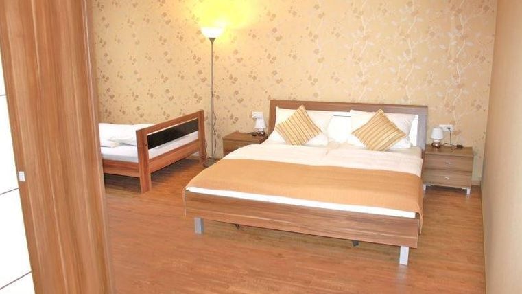 Une chambre confortable avec un grand lit double et un lit simple. Les murs sont clairs et décorés de motifs floraux.