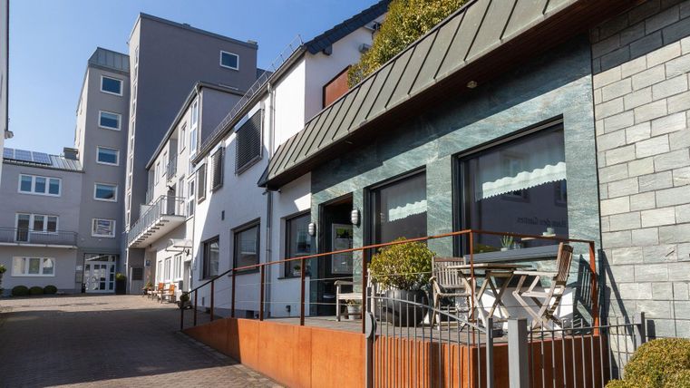 Een modern gebouw met een glazen façade en een groen buitengebied. De architectuur is eigentijds en nodigt uit om te verblijven.