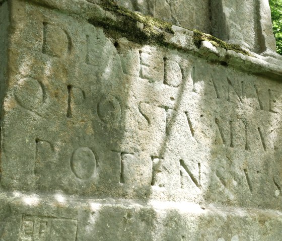 Gros plan d'une inscription antique sur un monument de pierre &eacute;rod&eacute; par le temps, entour&eacute; de mousse et de for&ecirc;t., &copy; Elke Wagner, Felsenland S&uuml;deifel Tourismus GmbH