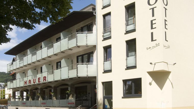 Ein modernes Hotel mit dem Namen "Hauer" und großen Fenstern. Die Fassade ist hell und hat einen einladenden Außenbereich.
