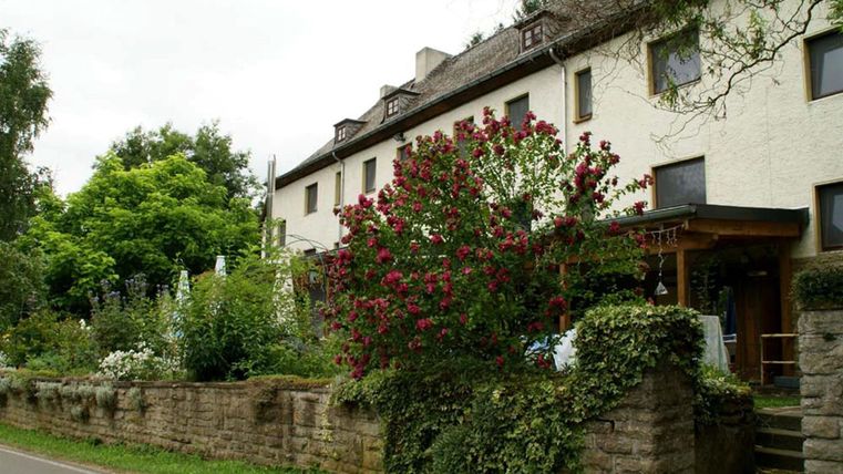 Ein charmantes Gebäude mit einem Garten voller Blumen und grüner Pflanzen. Die Umgebung ist ruhig und einladend.