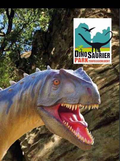 Ein Dinosaurierkopf vor einem Felsen mit dem Logo des Dinosaurierparks Teufelsschlucht.