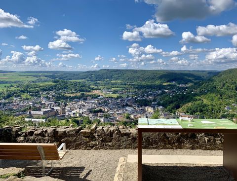 Ein malerischer Blick auf die Stadt von einem Aussichtspunkt aus. Das grüne Tal und der blaue Himmel mit Wolken schaffen eine entspannte Atmosphäre.
