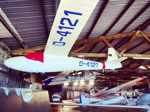 Ein Segelflugzeug hängt in einer Halle. Es ist weiß mit rotem Kopf und trägt die Kennung D-4121.