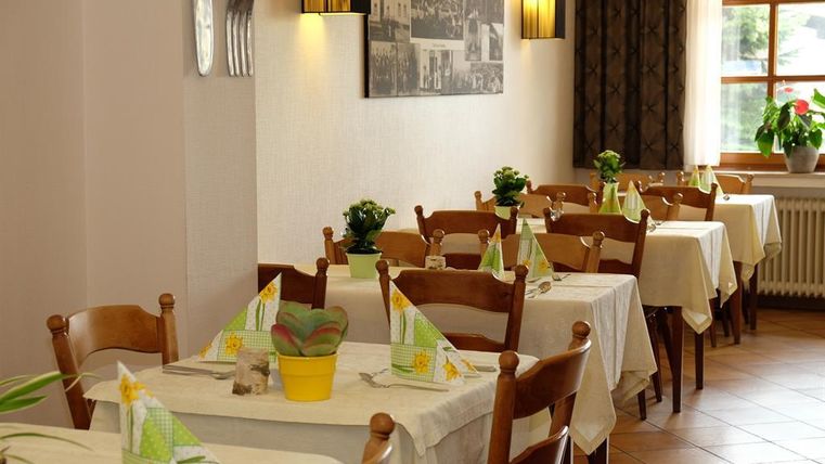 Ein gemütliches Restaurant mit einfachen, weißen Tischen und Stühlen. Die Tische sind mit bunten Servietten und kleinen Pflanzen dekoriert.