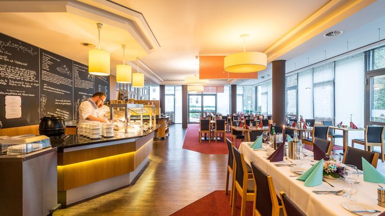 Ein modernes Restaurant mit einer gemütlichen Atmosphäre. Der Bereich ist hell erleuchtet und bietet eine ansprechend gedeckte Tafel.