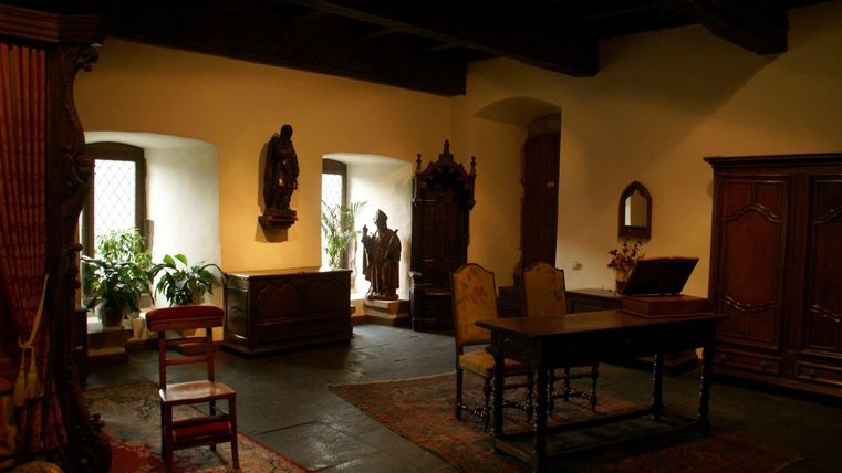 Ein gemütlicher Raum mit Holzdecke und mehreren Fenstern. Im Raum stehen ein Tisch, Stühle und einige dekorative Gegenstände.