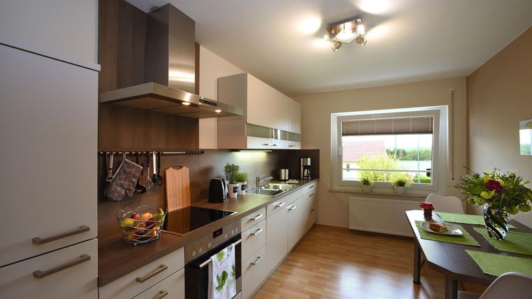 Eine moderne Küche mit Holz- und weißen Möbeln. Es gibt eine helle Atmosphäre und viel Platz für die Zubereitung von Mahlzeiten.