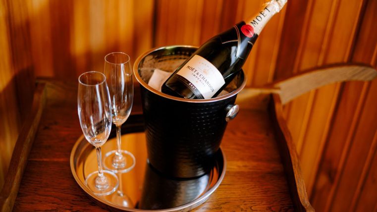 Een champagnefles in een ijsemmer staat op een dienblad. Daarnaast staan twee proseccoglazen.