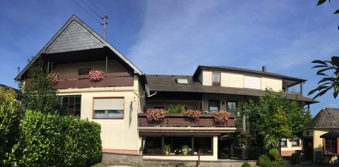 Ein schönes Gebäude mit Balkonen, die mit Blumen geschmückt sind. Der Himmel ist klar und blau, was eine freundliche Atmosphäre schafft.