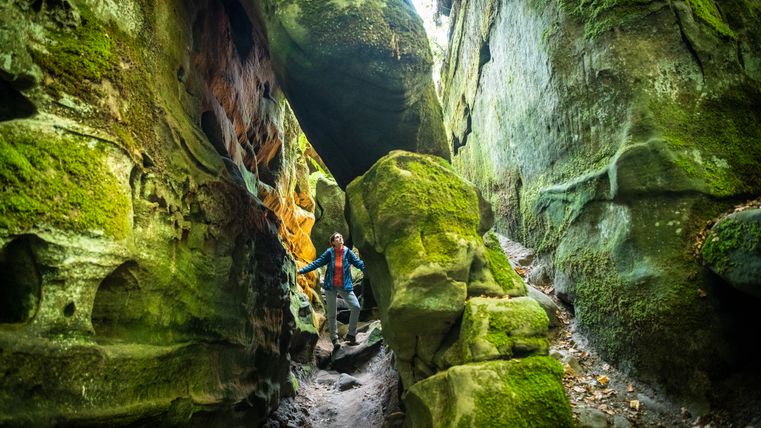 Person in einer moosbedeckten Felsenschlucht.