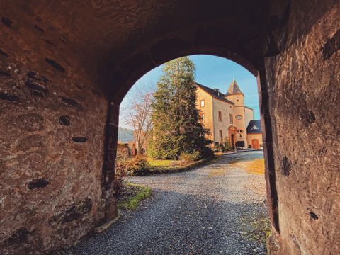 Vue unique à travers un arc sur un bâtiment historique avec un beau jardin et des arbres. La scène dégage une atmosphère calme et idyllique.